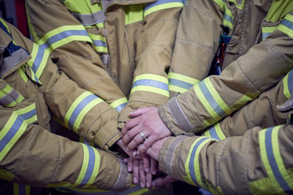 Foto van de handen van een team brandweermensen.