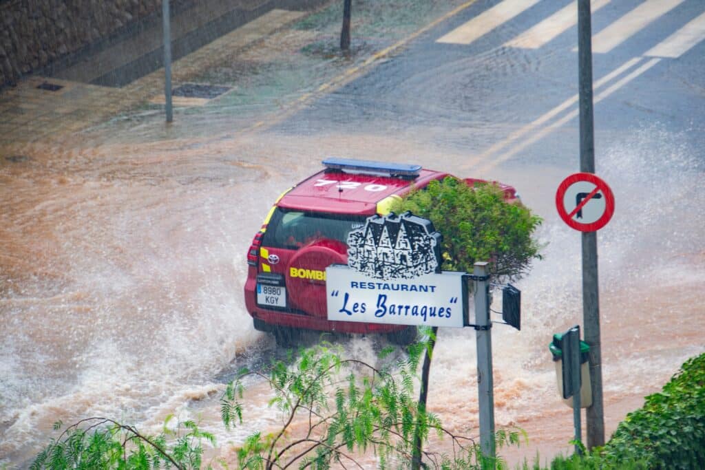 Auto rijdt in ondergelopen straat in Valencia als gevolg van de overstromingen