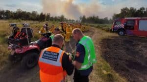 Landelijk adviseur overlegt met heliteam. Op de achtergrond zijn leden van de handcrew te zien.