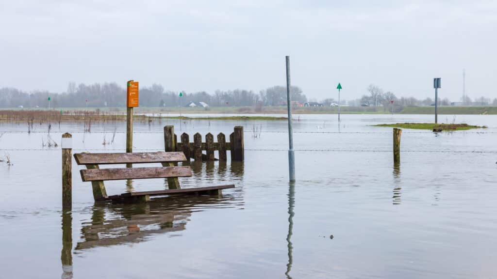 Houten bank staat in het water door hoogwater.