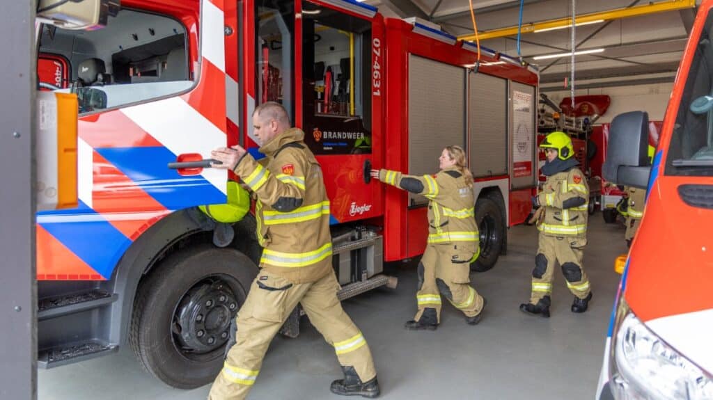 Brandweermensen stappen brandweerauto in, op weg naar een uitruk