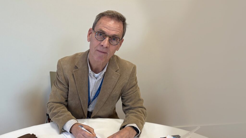 Koos Kranenburg kijkt in de camera met een pen in zijn hand.