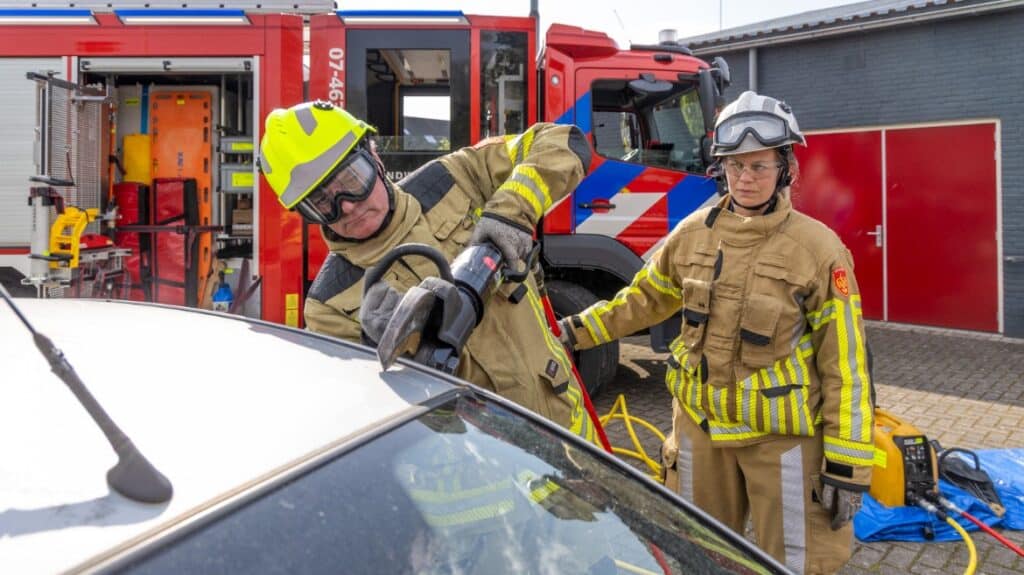 Foto: NIPV. Brandweerman opent auto met gereedschap.